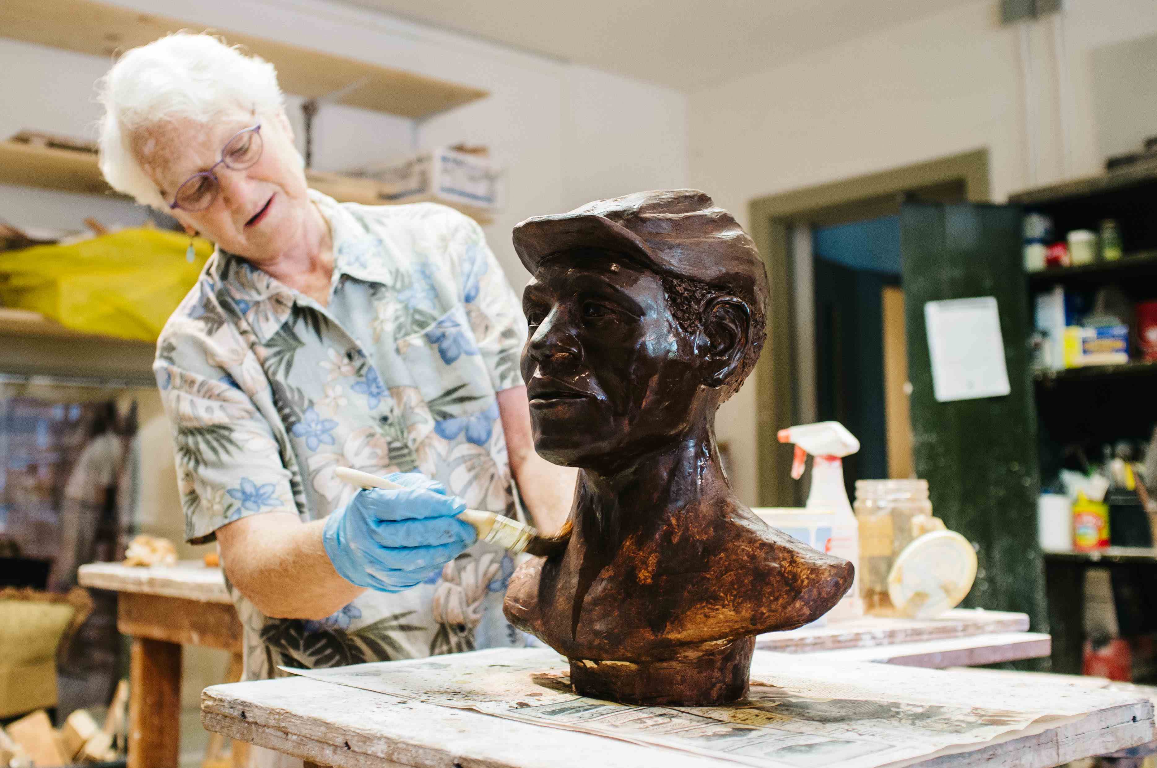 An older artist working on a bust.