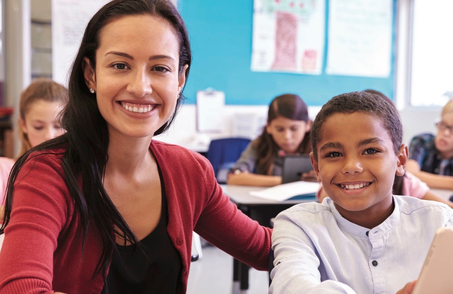 A teacher and student smile at the camera.