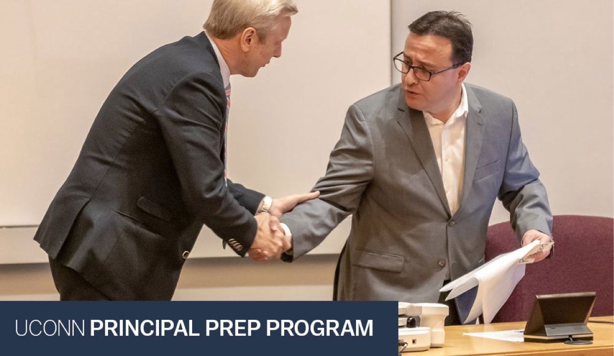 Two education leaders shake hands at the conclusion of a conference.