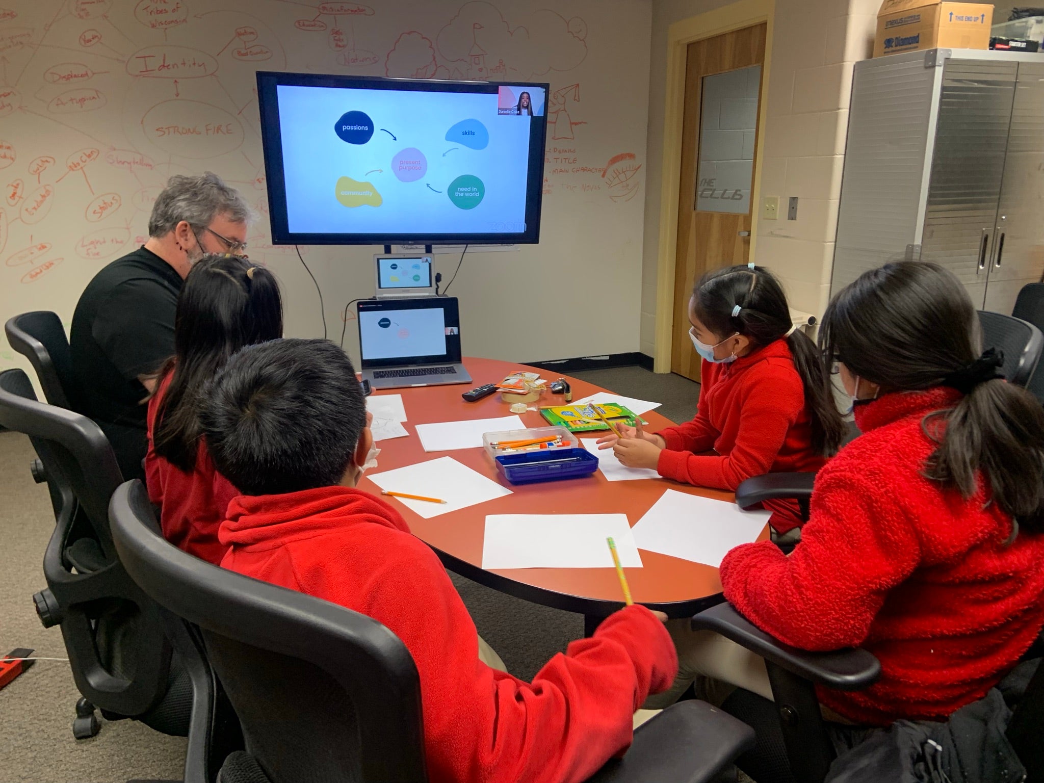 Students sit around a conference table looking at a presentation screen.