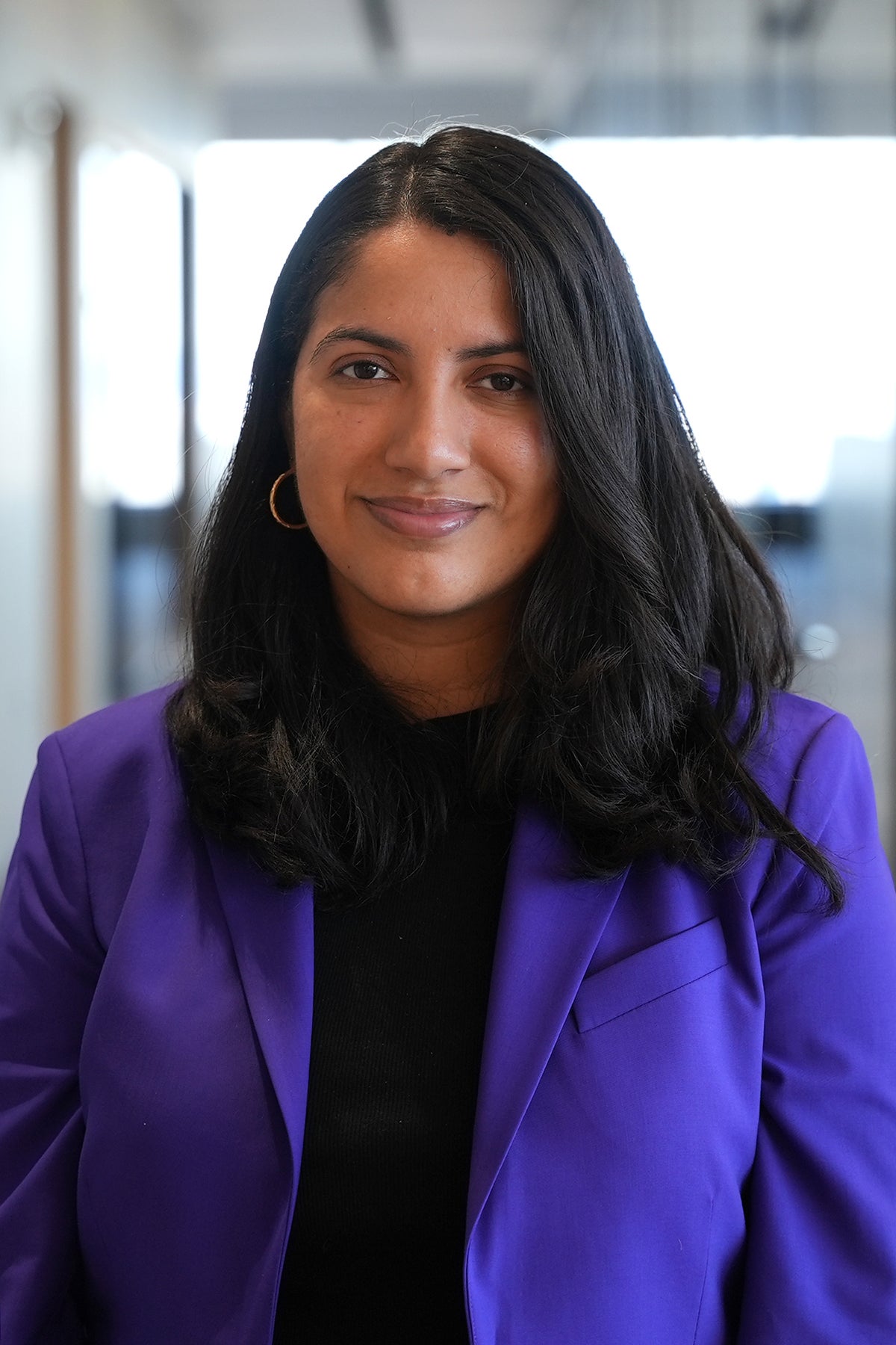 Aura Ochoa, PROGRAM ASSOCIATE, ARTS standing in a purple blazer